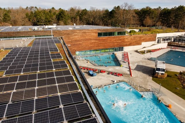 Außenansicht der Therme Wien Becken und Solarpaneelen am Dach