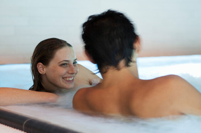 Junges Paar liegt entspannt in einem Becken der Therme Wien.